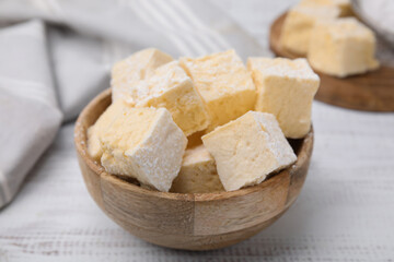 Bowl with tasty marshmallows on white wooden table, closeup