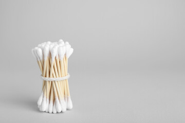 Fototapeta na wymiar Bunch of wooden cotton buds on light grey background. Space for text