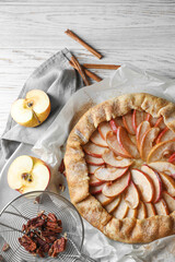 Delicious apple galette, cinnamon and pecans on table, flat lay