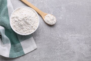Bowl and spoon with bean flour on light grey table, flat lay. Space for text