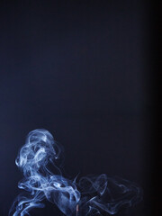 incense smoke creating shapes on a dark blue background