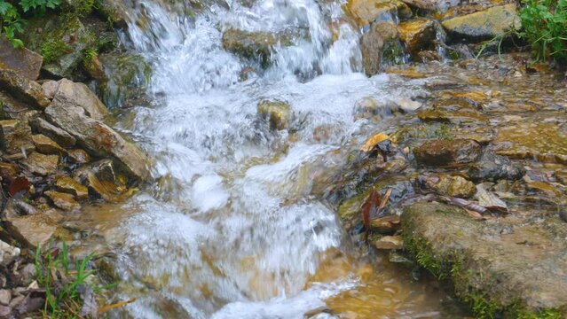 Transparent waterfall, brook flowing down rocky hill in summer day. One of the Slavonic springs in vicinity of Izborsk which are considered to be holy and healing. Pskov region, Russia. 4K UHD 2160p