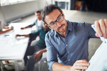 The creative process. Shot of a mature man writing on a whiteboard while giving a presentation to colleagues in an office.