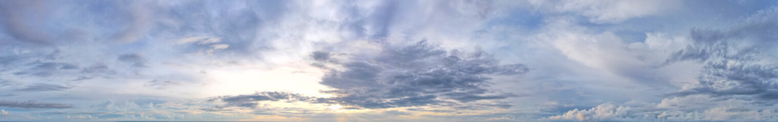 The soft blue sky is covered with light blue clouds. obscuring the sun with dark blue clouds