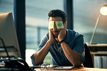 No time to sleep. Shot of a tired young businessman working late in an office with adhesive notes...