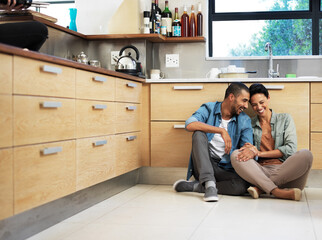 Theyre home is filled with love and laughter. Shot of a smiling young couple sitting together on their kitchen floor.