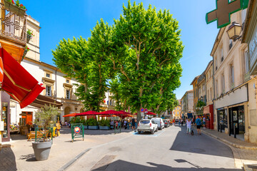 A small town square with shops, trees, and sidewalk cafes in the historic old town of Saint-Remy-de-Provence, France, in the Provence Cote d'Azur region of the French Riviera. © Kirk Fisher