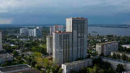 Fototapeta na wymiar Drone view of tall houses under construction. Stock footage.A built-up city next to a lake against a gray sky.
