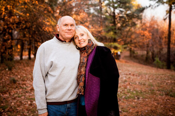 Senior citizen couple standing in a forest in autumn