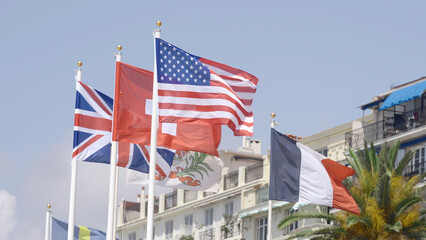 Row of waving flags of different countries. Action. Concept of politics, waving flags on a blue sky and building background.