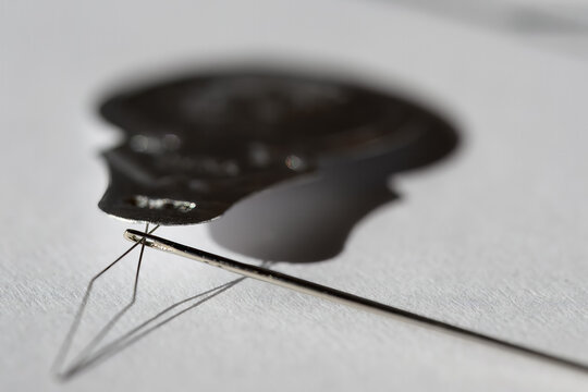 Sewing needle threader tool in use and a single black string. 