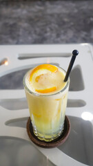 Ice squeezed orange or orange juice in a tall glass at the table