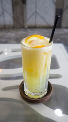 Ice squeezed orange or orange juice in a tall glass at the table