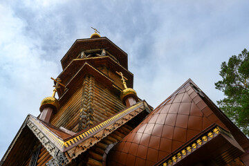 Fototapeta na wymiar Bottom view of the wooden tower of the Christian Orthodox Church against the rainy sky