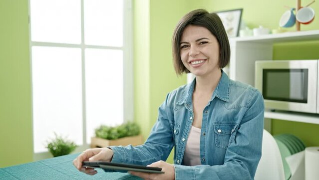 Young caucasian woman using touchpad sitting on table at home