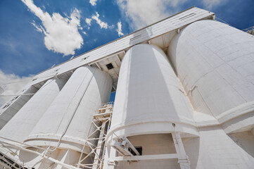 White cement silo towers under blue sky with clouds