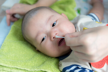 Cleaning Baby Nose With cotton swab, Mother using cotton swap pick up nose a newborn baby