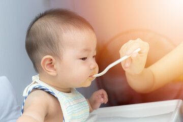 Asia baby boy child sitting eating food on chair at home
