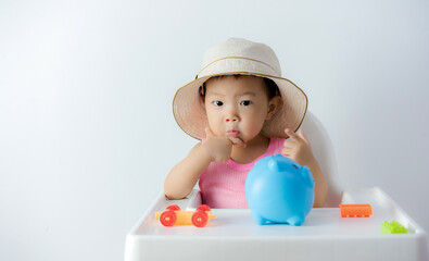 Baby boy inserting a coin into a piggybank on white background - financial concept