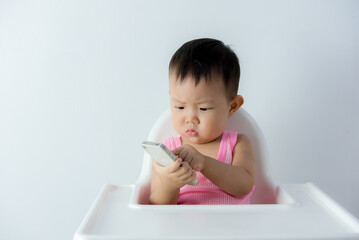 asia baby boy sitting on chair in the living room and playing with smartphone