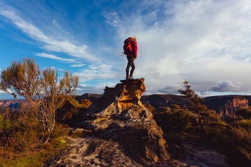 Woman hiker standing on top of rock precipice with grand views