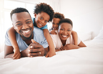 Happy, bonding and portrait of a black family on a bed for playing, quality time and comfort....