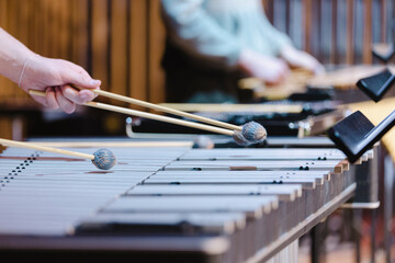A musician playing a vibrophone with gray mallets during a casual wind ensemble rehearsal