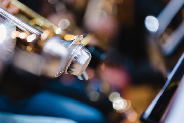 A musician playing a trumpet with a damaged mute in a trumpet section of an orchestra rehearsal
