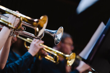 A musician playing a trumpet in a trumpet section of an orchestra during rehearsal