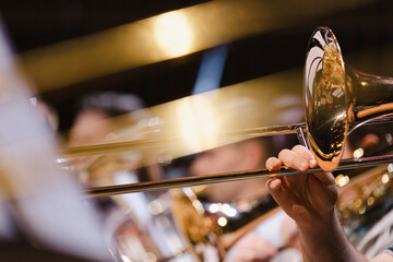 A musician playing a trombone during a casual wind ensemble rehearsal just before the concert - obrazy, fototapety, plakaty