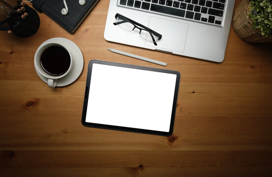 Flat lay, top view. Digital tablet with empty screen, coffee cup and glasses on wooden table.