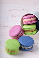 Colorful macaroons crumble from a white cup