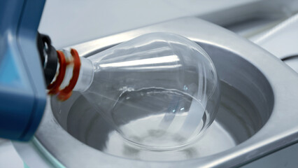 Close up of mechanism rotating clean glass flask. Stock footage. Medical or chemical laboratory equipment.