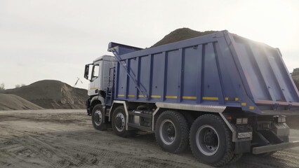 Mining dump truck working at the sand quarry. Scene. Industrial background at the quarry or at the construction site.