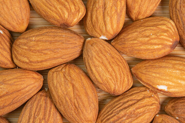 Almond nuts on wooden background close up. Product rich in minerals and vitamins. Almond kernels. Healthy skin and hair and natural healing oil treatment