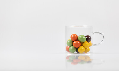 Naklejka na ściany i meble Colorful chocolate balls in a glass cup.