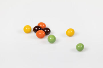 Colorful chocolate balls are irregularly placed on a white background.