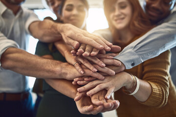 Success belongs to those who grab it. Shot of a group of colleagues joining their hands in solidarity at work.