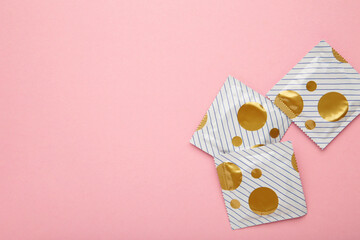 Condoms package on pink background. A condom use to reduce the probability of pregnancy or sexually...