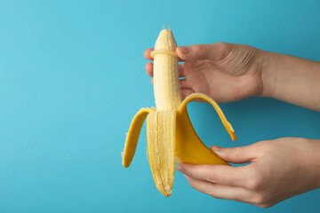 Female hand puts on a condom on a banana. Safe sex concept.