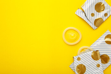 Opened condom in pack on yellow background. A condom use to reduce the probability of pregnancy or...
