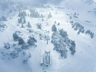 aerial view diffused light over ski lift in hahnenkamm ski resort with multiple slopes and snowy trees