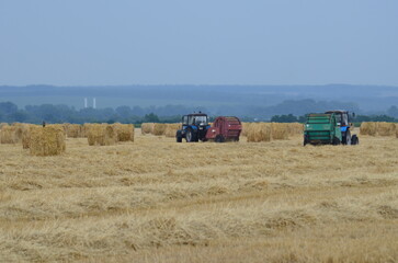 tractors on a mown wheat field stack haystacks