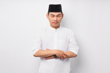 Portrait Handsome young Asian Muslim man wearing Arabic costume standing while doing praying to god or shalat isolated on white background. People religious Islamic lifestyle concept