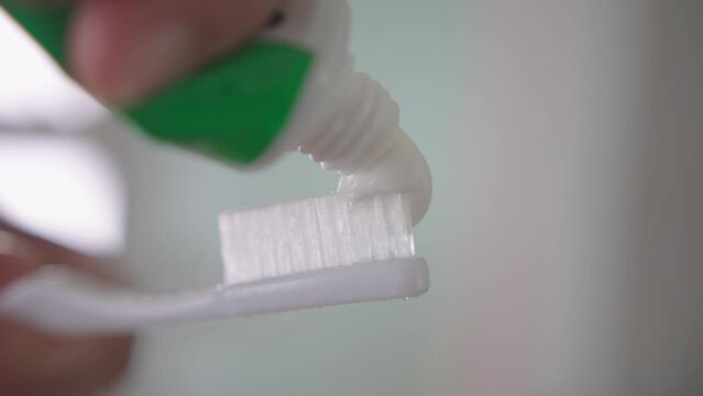 Squeezing white toothpaste from a tube onto toothbrush. Brushing her teeth, morning and evening procedures