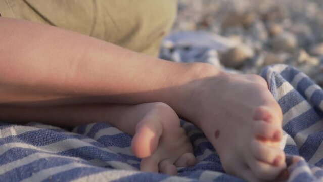 Close-up of a boy's feet on a pebble beach, a child on a towel