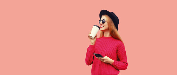 Portrait of stylish young woman drinking coffee with smartphone looking away wearing sweater, black...