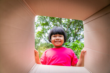 Asian children playing in cardboard boxes