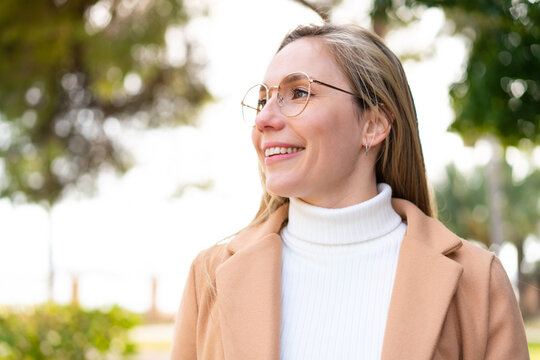 Young blonde woman at outdoors With glasses with happy expression