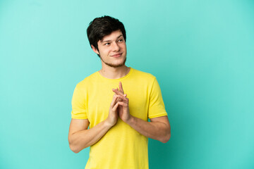 Young Russian man isolated on blue background scheming something